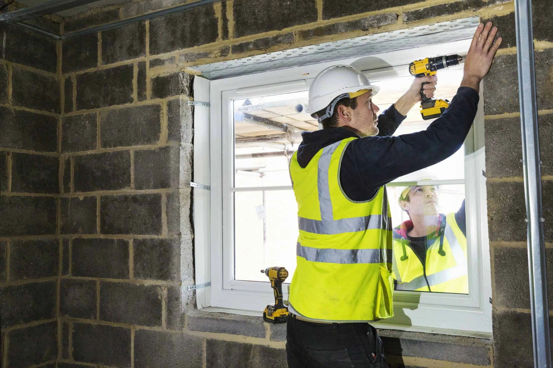 A construction worker installing a window in a brick wall for B2B Windows and Doors.