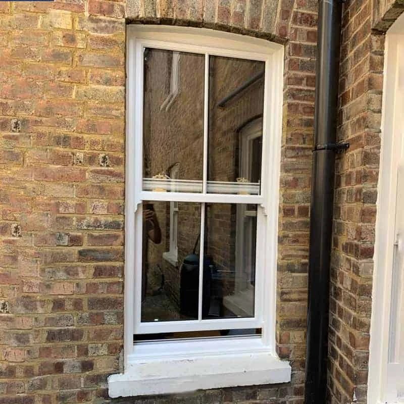 A white window in a brick house.