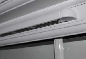 A close up view of a white air conditioning unit with trickle vents.